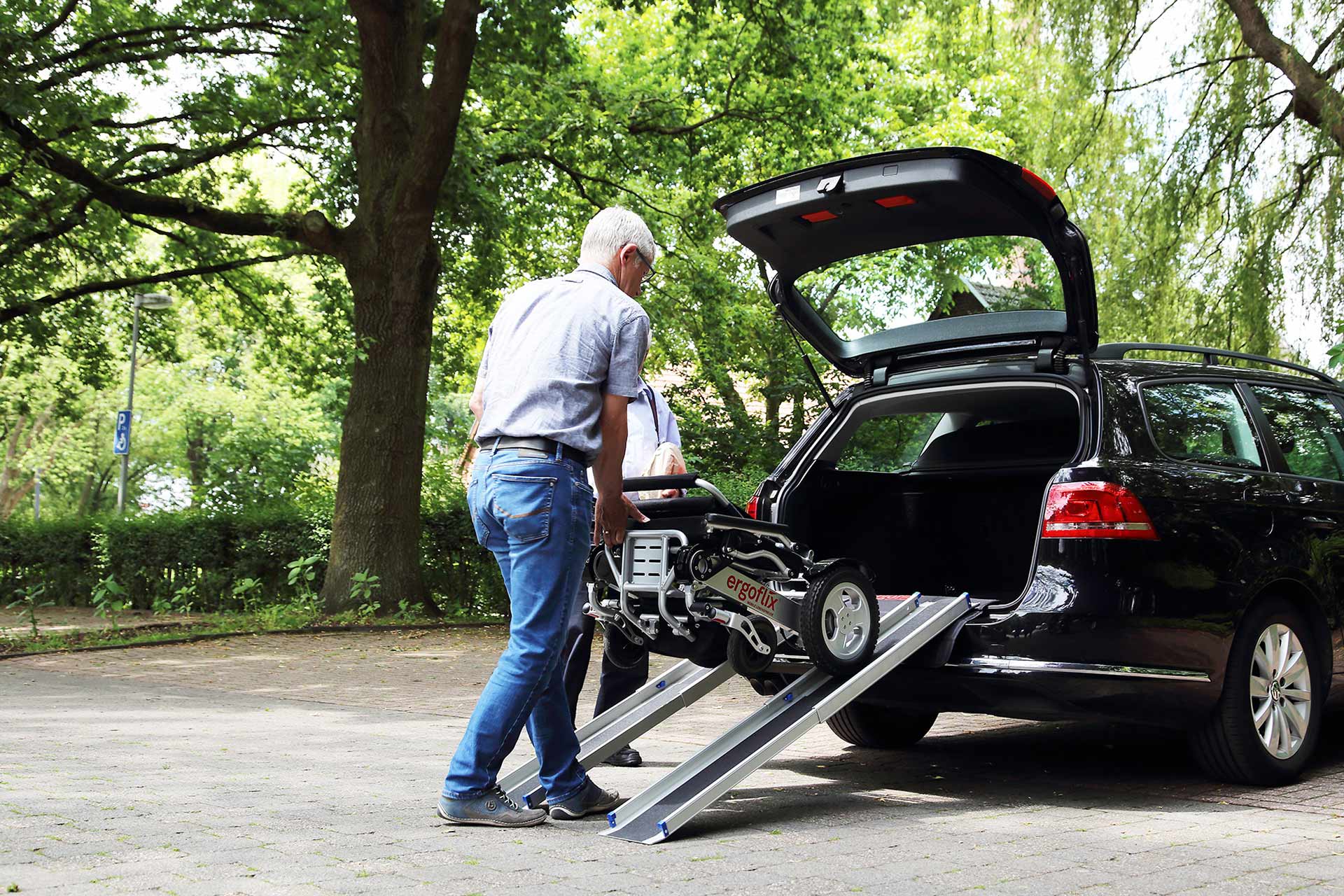 Folded Ergoflix electric wheelchair being loaded into a car boot