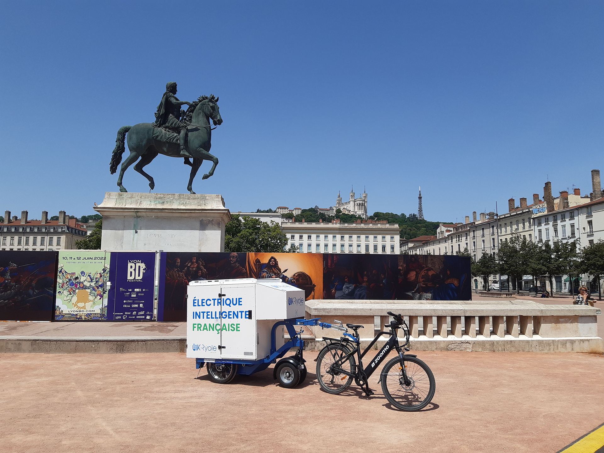 Vélo Zoomo et remorque électrique K-Ryole, stationnés sur la place Bellecour à Lyon