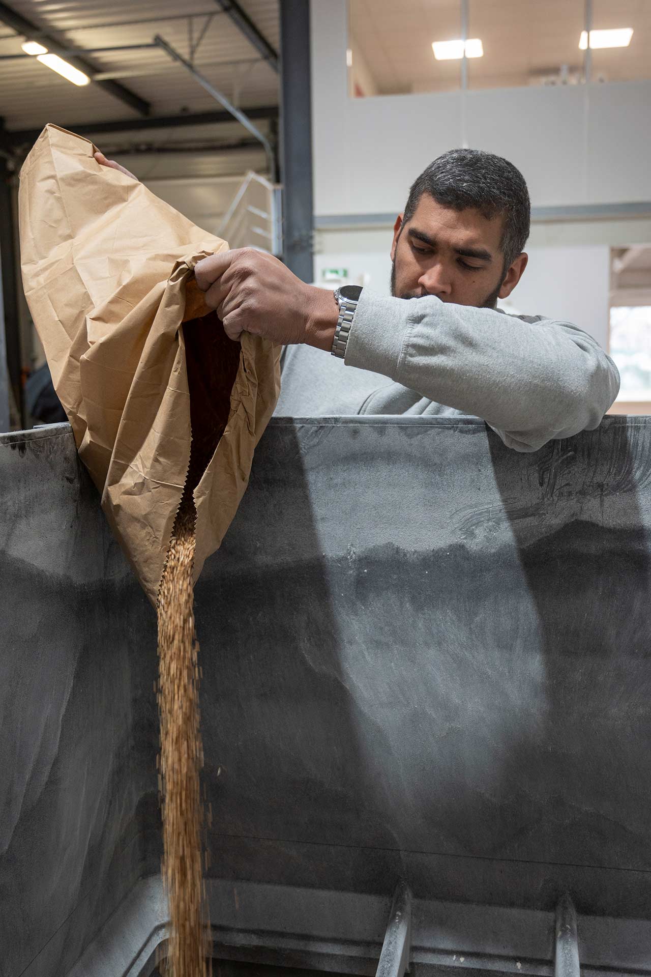 Grains de blé versés dans un moulin à farine (moulin à projection) par Nicolas, chef d’atelier de la meunerie Gaston Meunier Bio, installée à Pierre-Bénite (métropole de Lyon)
