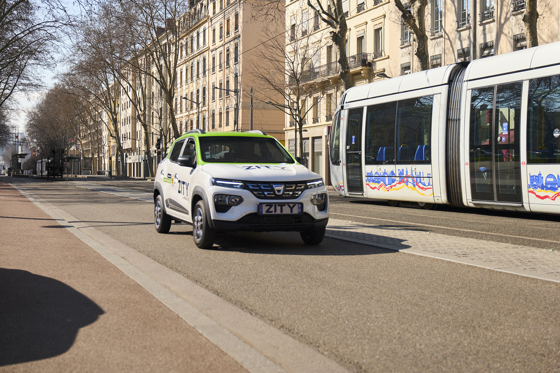 Voiture Zity roulant à côté d'un tramway à Lyon